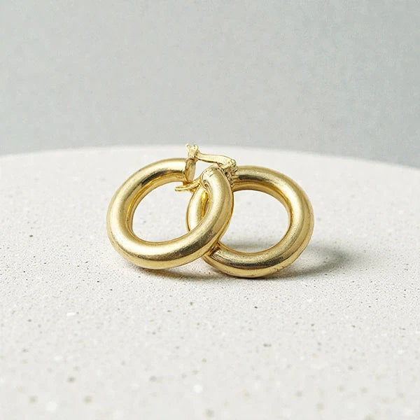 représentation de créoles fines dorées sur fond blanc soie