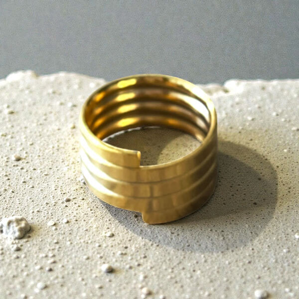 Représentation de la bague spirale dorée à l'or fin 24 carats sur fond studio gris.