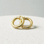 Boucles créoles tubes dorées  l'or fin 24 carats sur fond studio gris