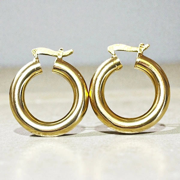 Représentation des boucles tubes dorées à l'or fin 24 carats sur fond studio