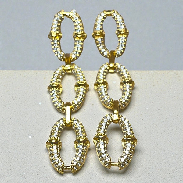 Représentation des boucles pendantes Secure dorées à l'or fin 24 carats sur fond studio gris