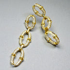 Représentation des boucles pendantes Secure dorées à l'or fin 24 carats sur fond studio